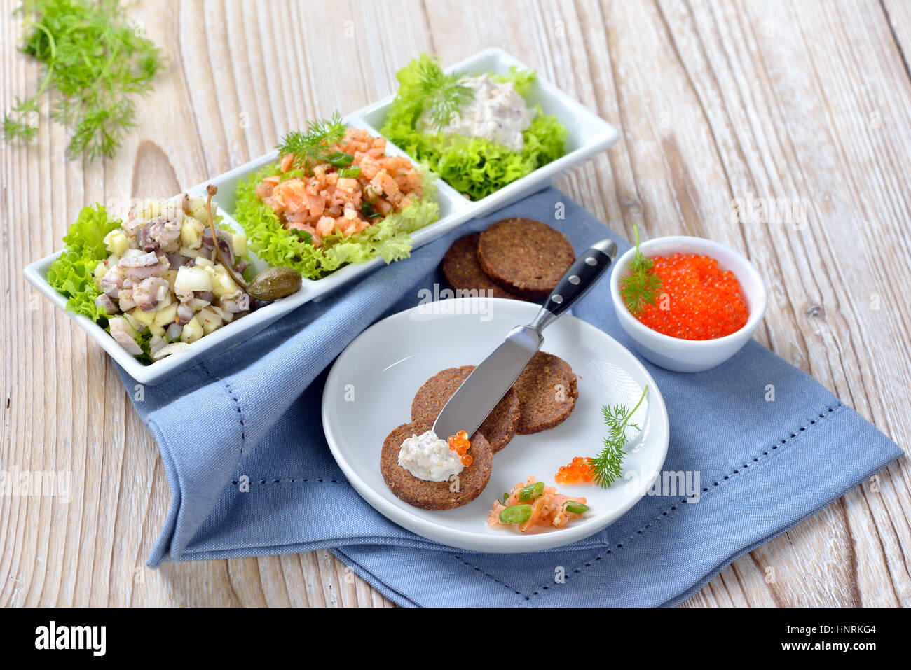 Poisson froid mixtes snack avec tartare de saumon fumé, mousse de truite, hareng salé du caviar et de la salade, servi en apéritif avec du pain pumpernickel Banque D'Images