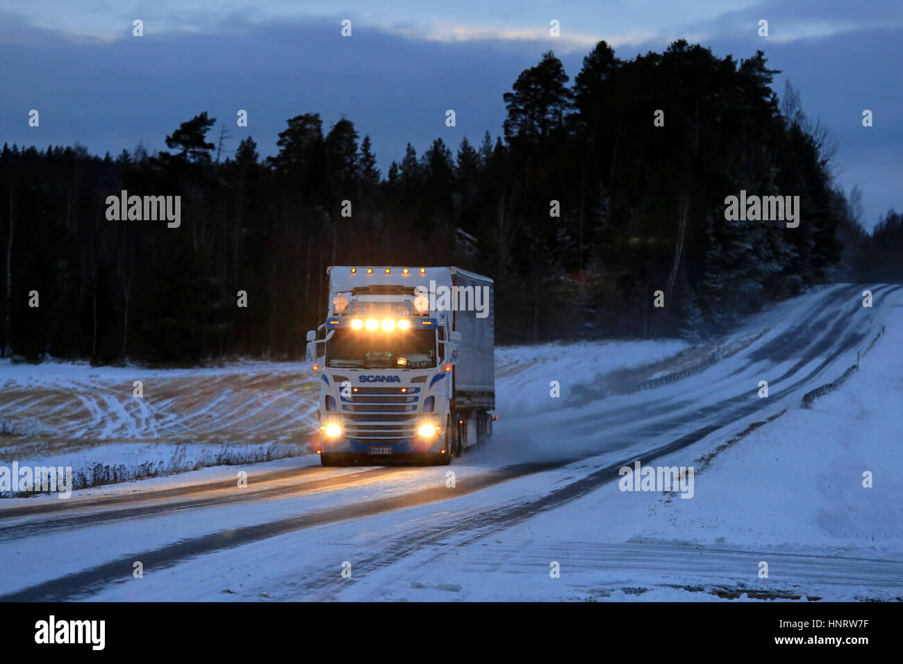 SALO, FINLANDE - le 7 janvier 2017 : Super personnalisées Scania semi truck de T. Salminen Transport avec phares brillants transporte des marchandises à dusktime le long de la neige Banque D'Images