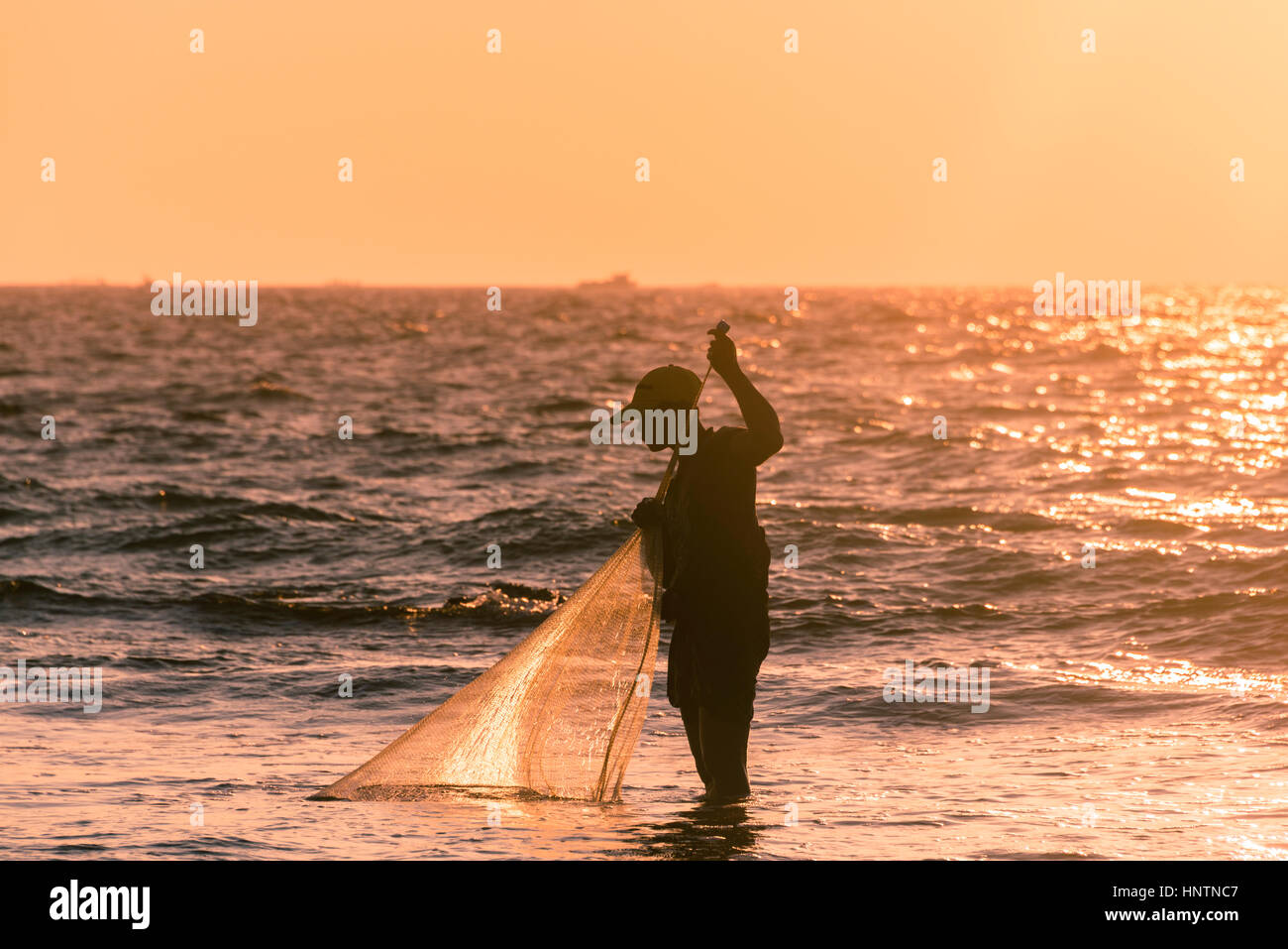 Les pêcheurs locaux avec filet de pêche en contre-jour, le coucher du soleil, Chaung Thar plage, baie du Bengale, de l'Ayeyarwady, au Myanmar Banque D'Images