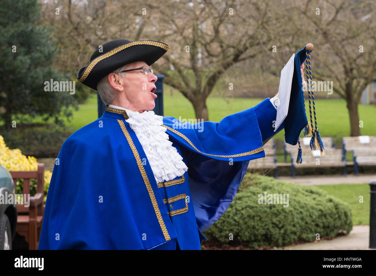 Crieur de ville masculin fait une annonce publique forte (costume bleu, chapeau tricorne, jabot de dentelle et volants, vieille tradition) - Ilkley, West Yorkshire, Angleterre Royaume-Uni. Banque D'Images