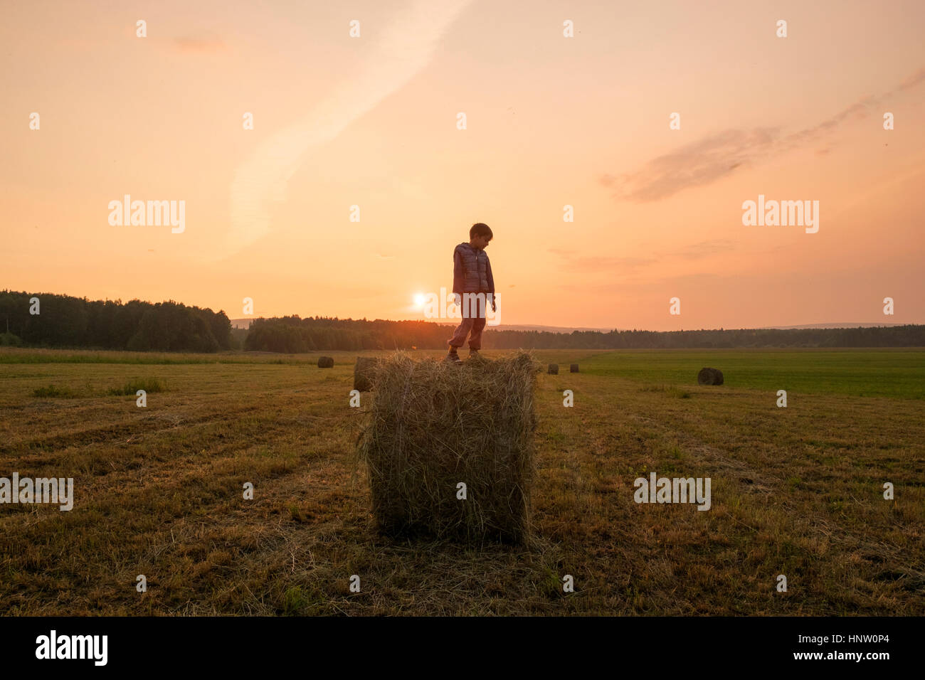 Mari boy standing on hay bale in field, de l'Oural, Russie Banque D'Images