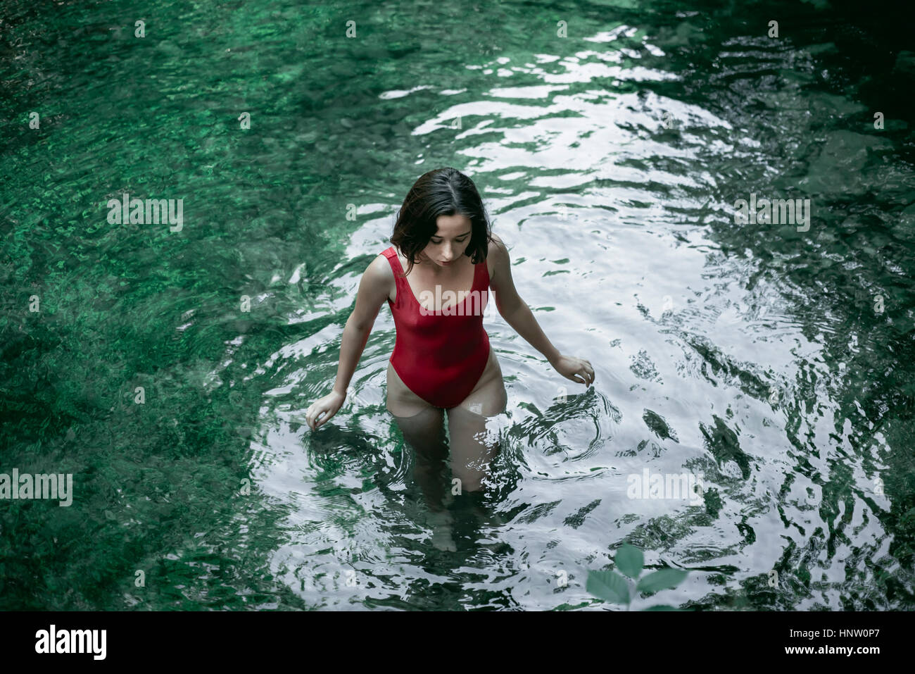 Caucasian woman de patauger dans l'eau de piscine Banque D'Images