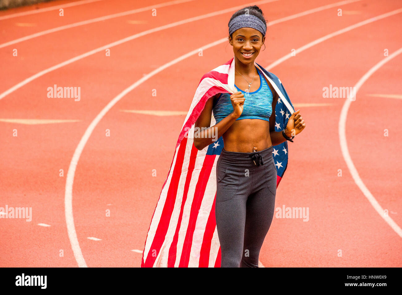 Smiling Black sportif posant avec le drapeau américain sur la voie Banque D'Images