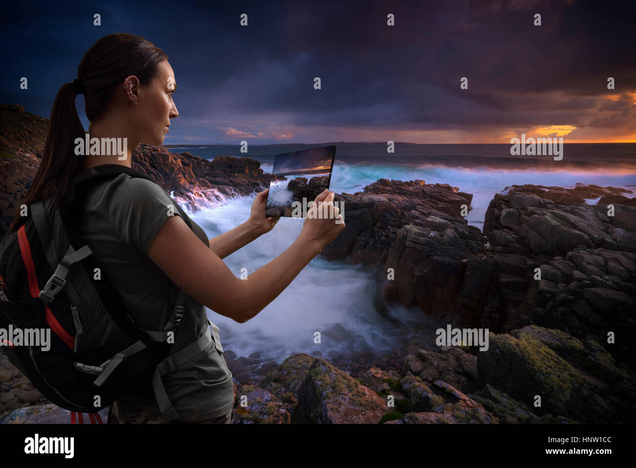 Caucasian woman photographing ocean sunset with digital tablet Banque D'Images