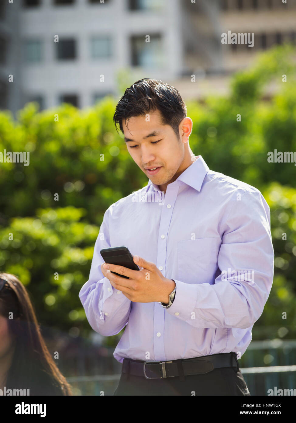 Chinese businessman texting on cell phone outdoors Banque D'Images