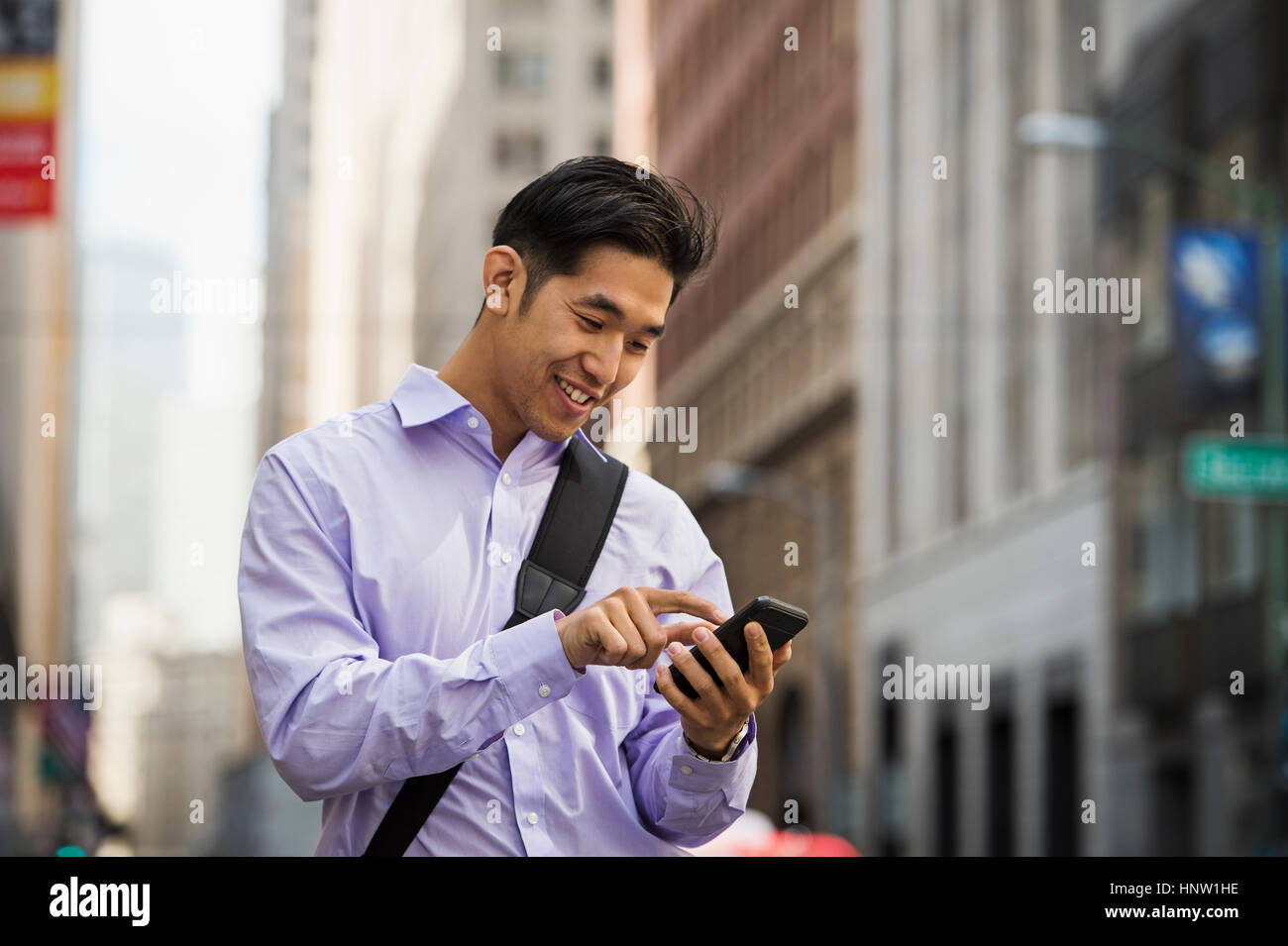 Chinese businessman texting on cell phone in city Banque D'Images