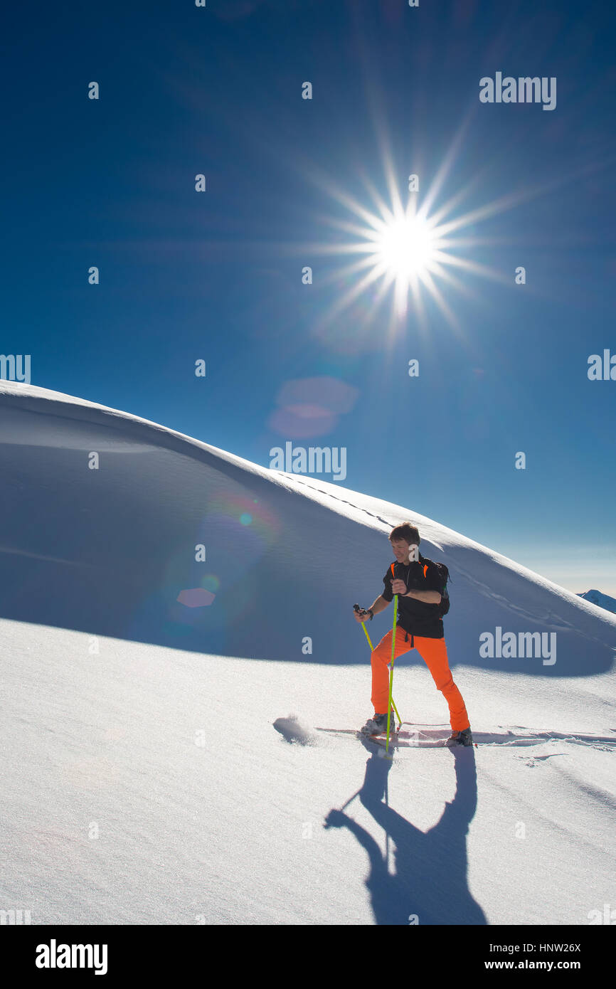 Un homme la skieuse alpine monter sur des skis et peaux dans de la neige fraîche dans un jour ensoleillé Banque D'Images