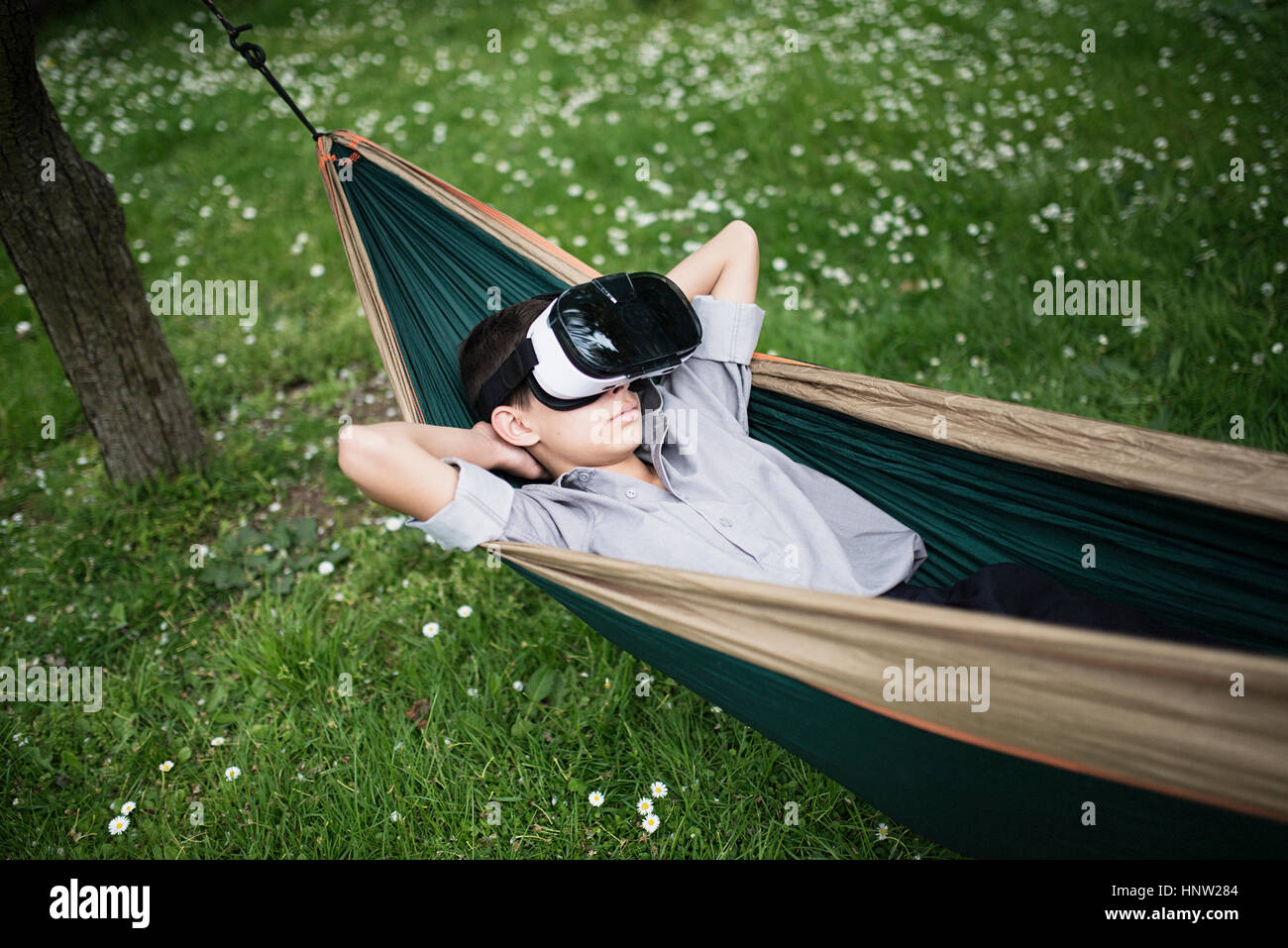 Mixed Race boy laying in hammock portant des lunettes de réalité virtuelle Banque D'Images