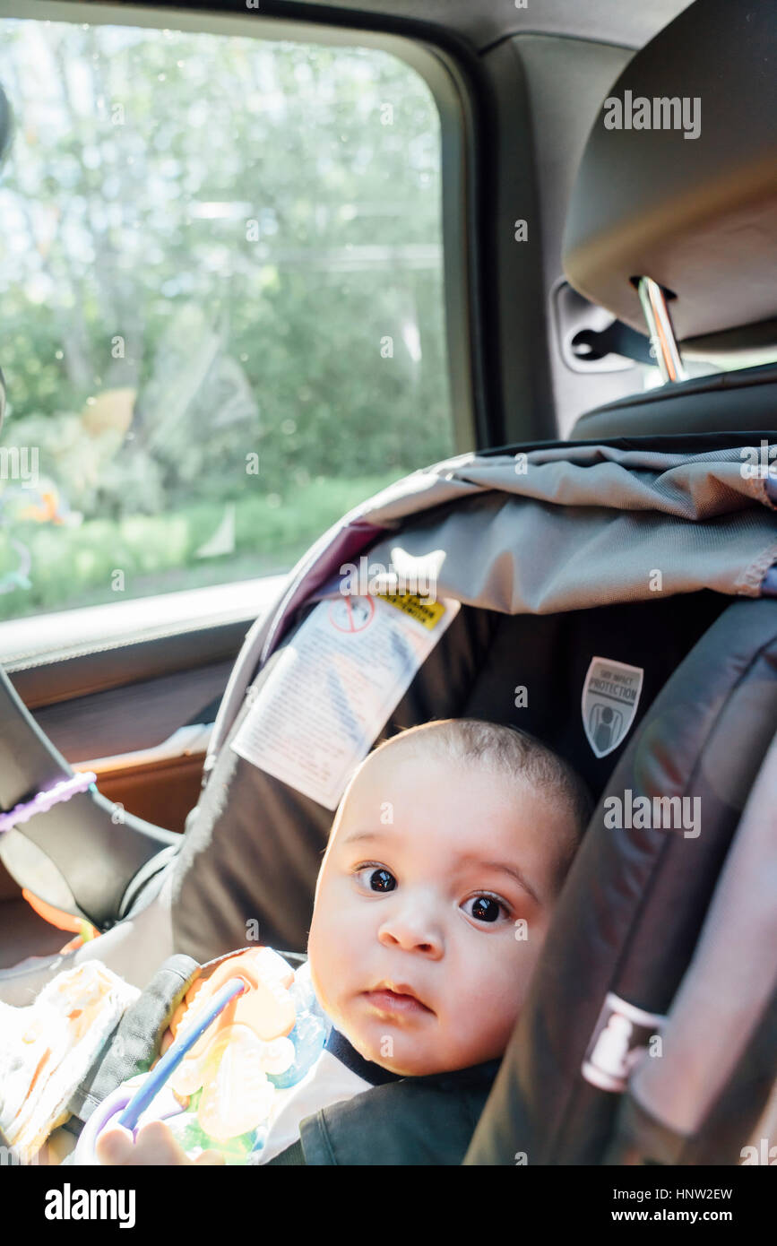 Portrait de curieux Mixed Race baby boy in car seat Banque D'Images