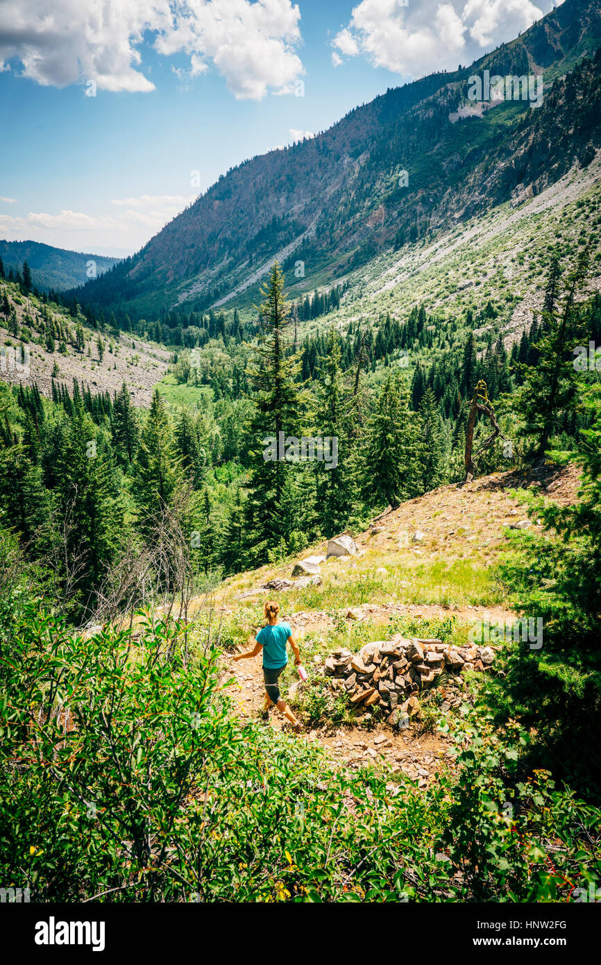 Caucasian woman hiking en descente sur chemin dans la montagne Banque D'Images