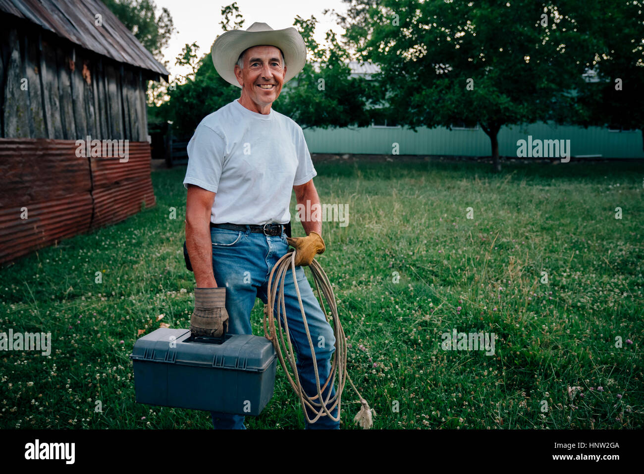 Caucasian farmer transportant la corde et boîte à outils Banque D'Images