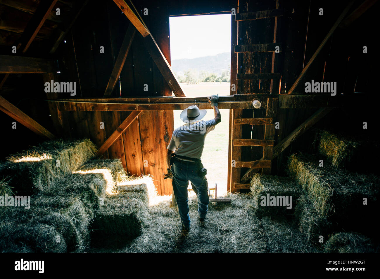 Caucasian farmer se reposant dans une grange près de bottes de foin Banque D'Images