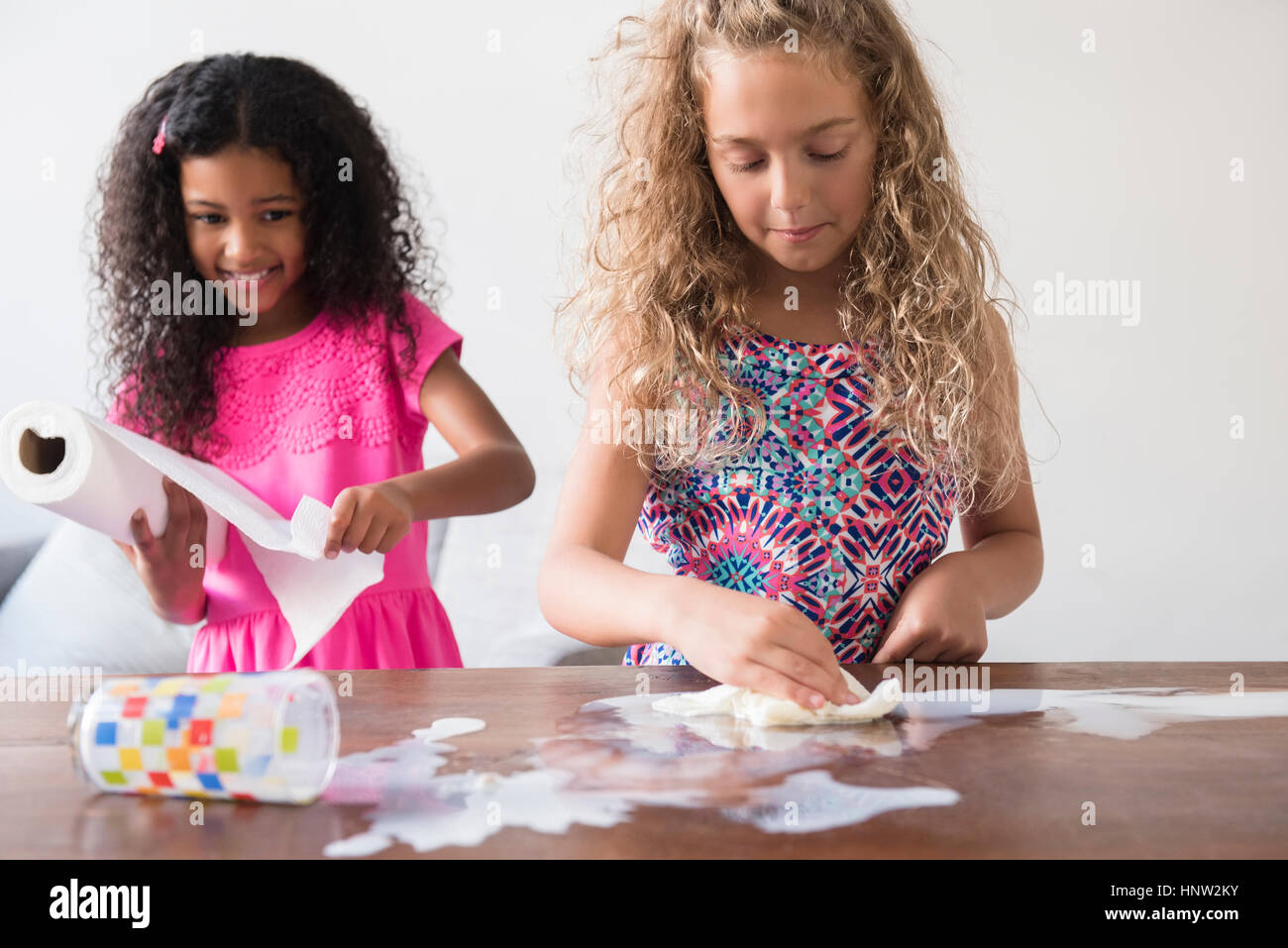 Nettoyage filles lait renversé sur la table Banque D'Images Nettoyage filles lait renversé sur la table Banque D'Images