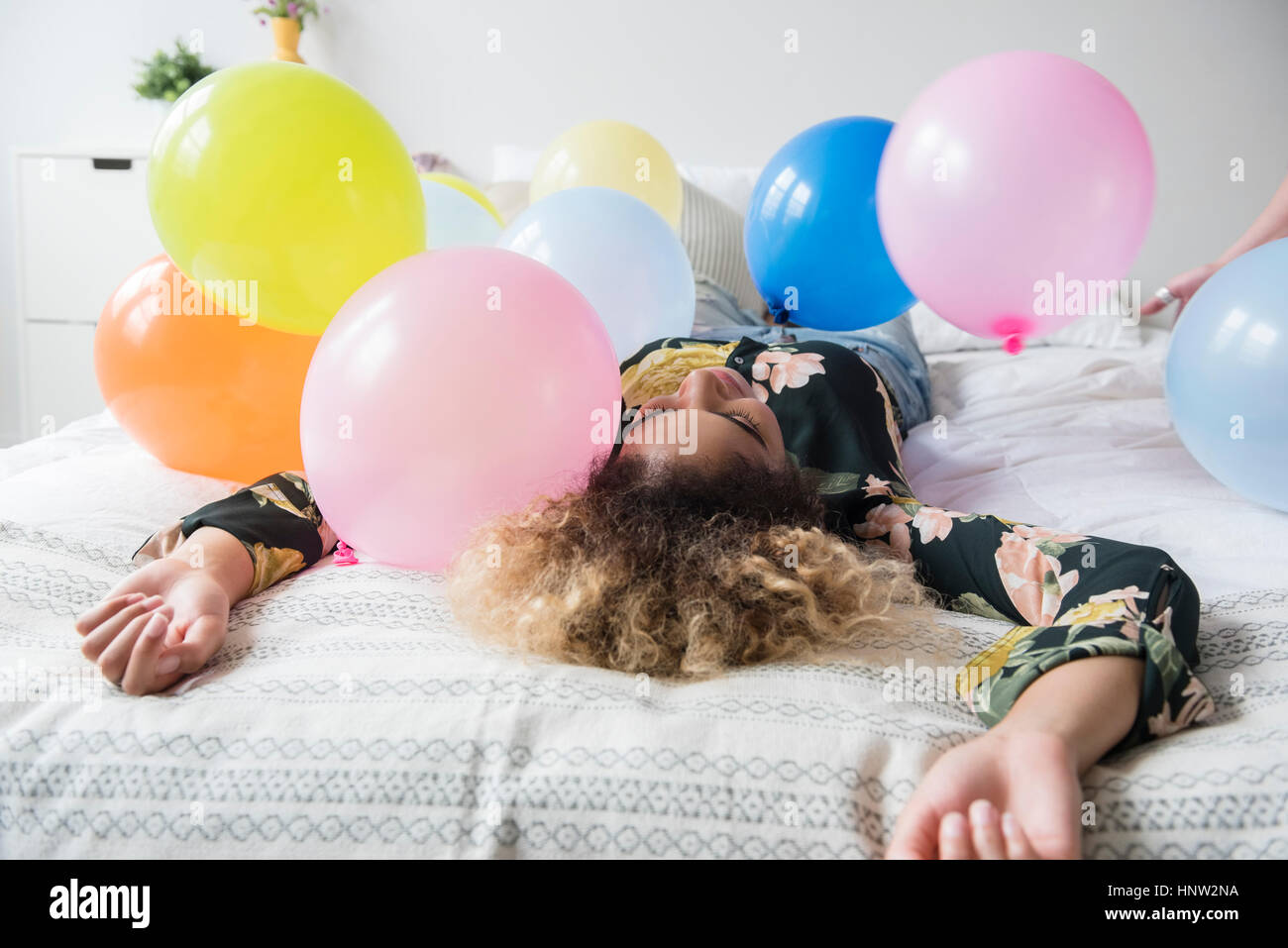 Mixed Race woman sitting on bed couverts avec des ballons Banque D'Images