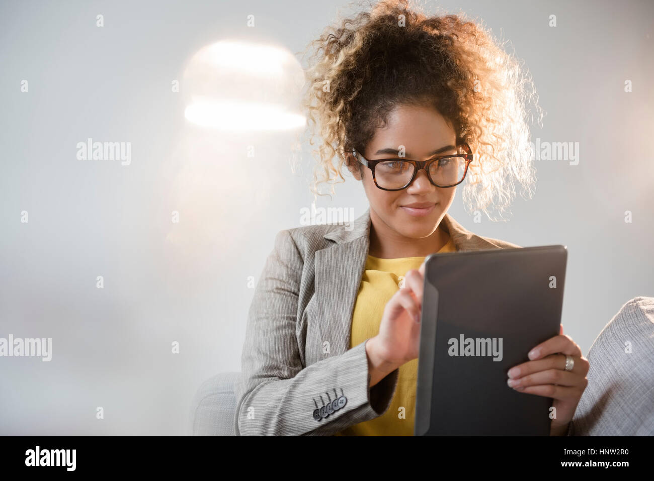 Mixed Race woman wearing eyeglasses using digital tablet Banque D'Images