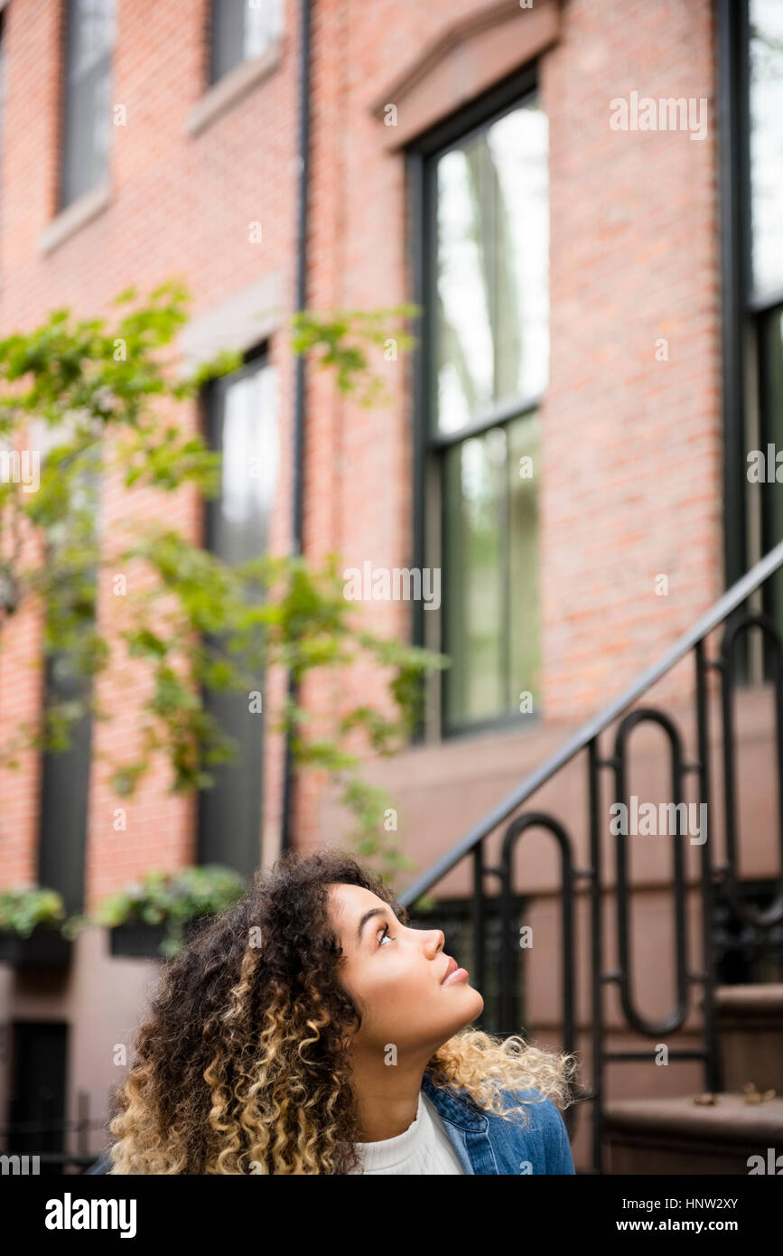 Curieux Mixed Race woman looking up in city Banque D'Images