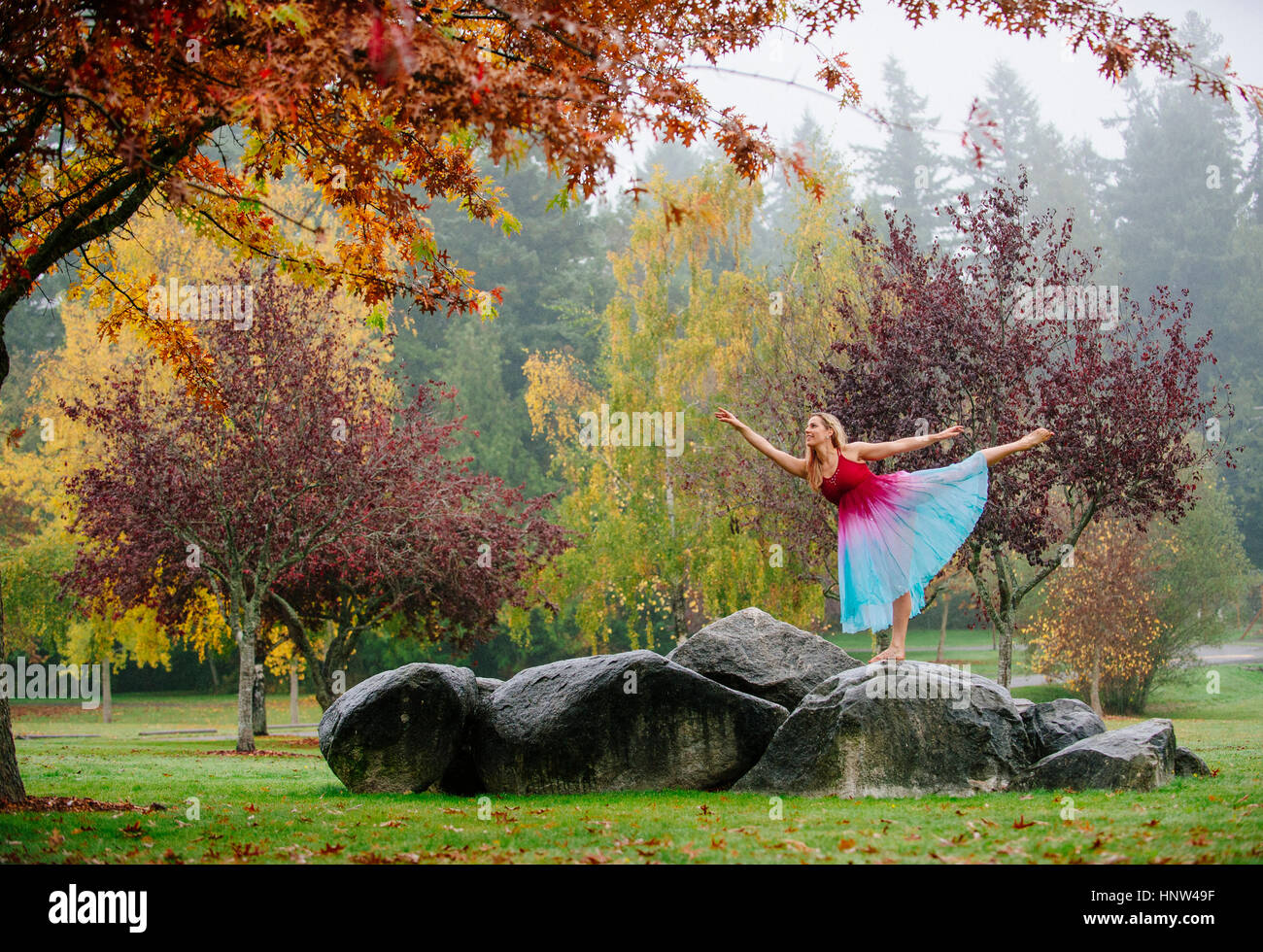 Caucasian ballerina dancing on rocks in park Banque D'Images