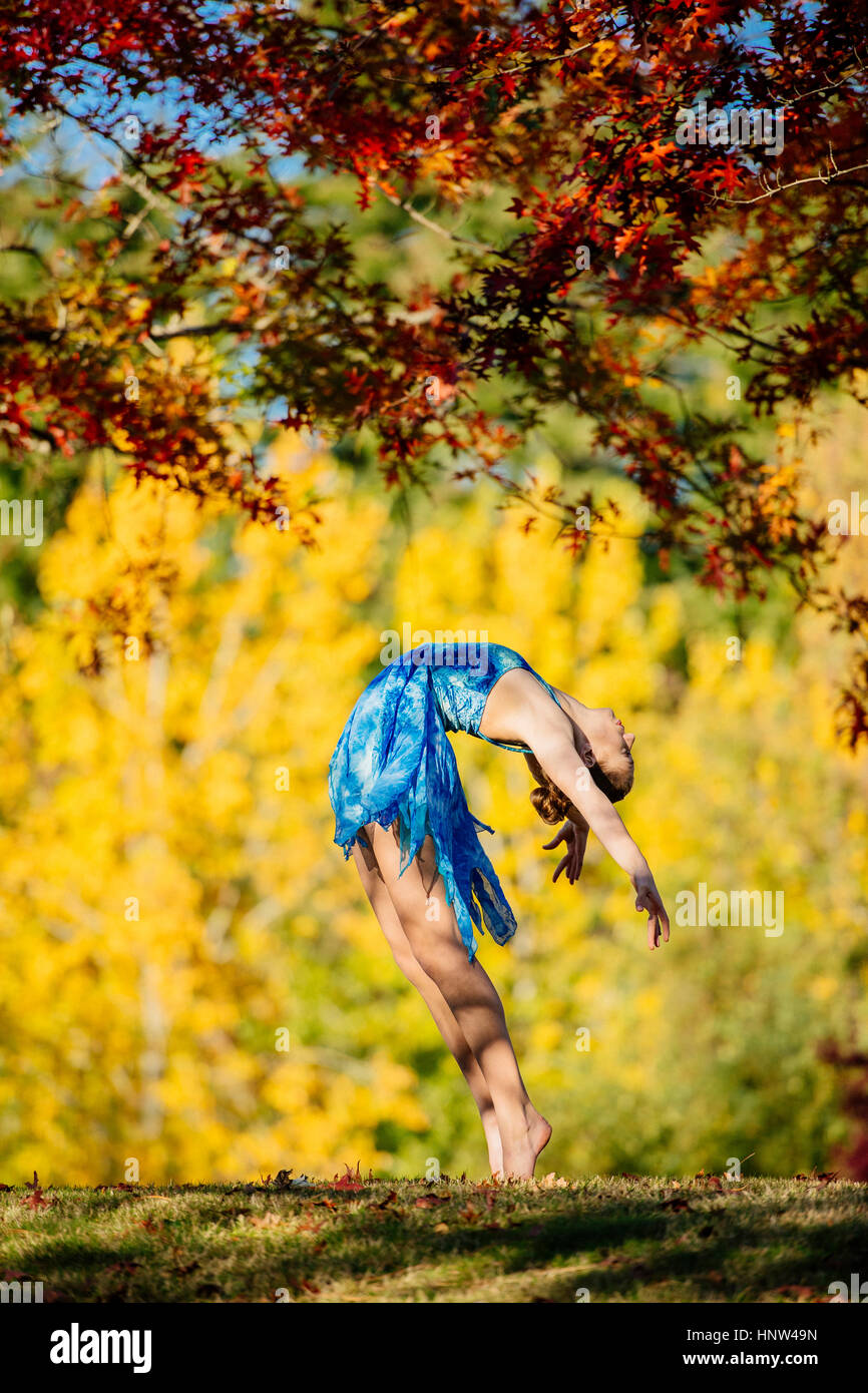 Caucasian ballerina danser sous des branches dans park Banque D'Images