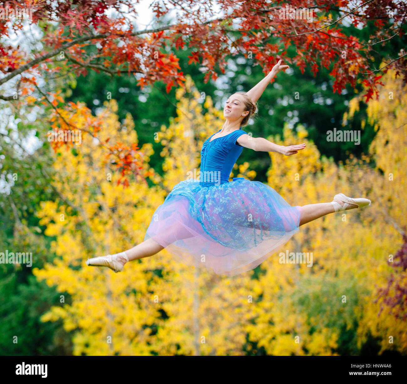 Caucasian ballerina sautant sous branches in park Banque D'Images