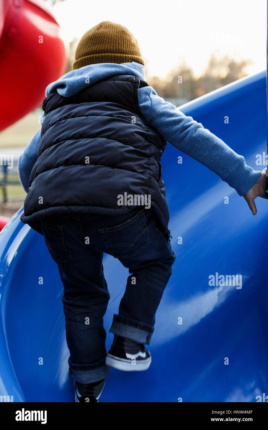 Mixed Race boy climbing sur bleu aire de glisse Banque D'Images