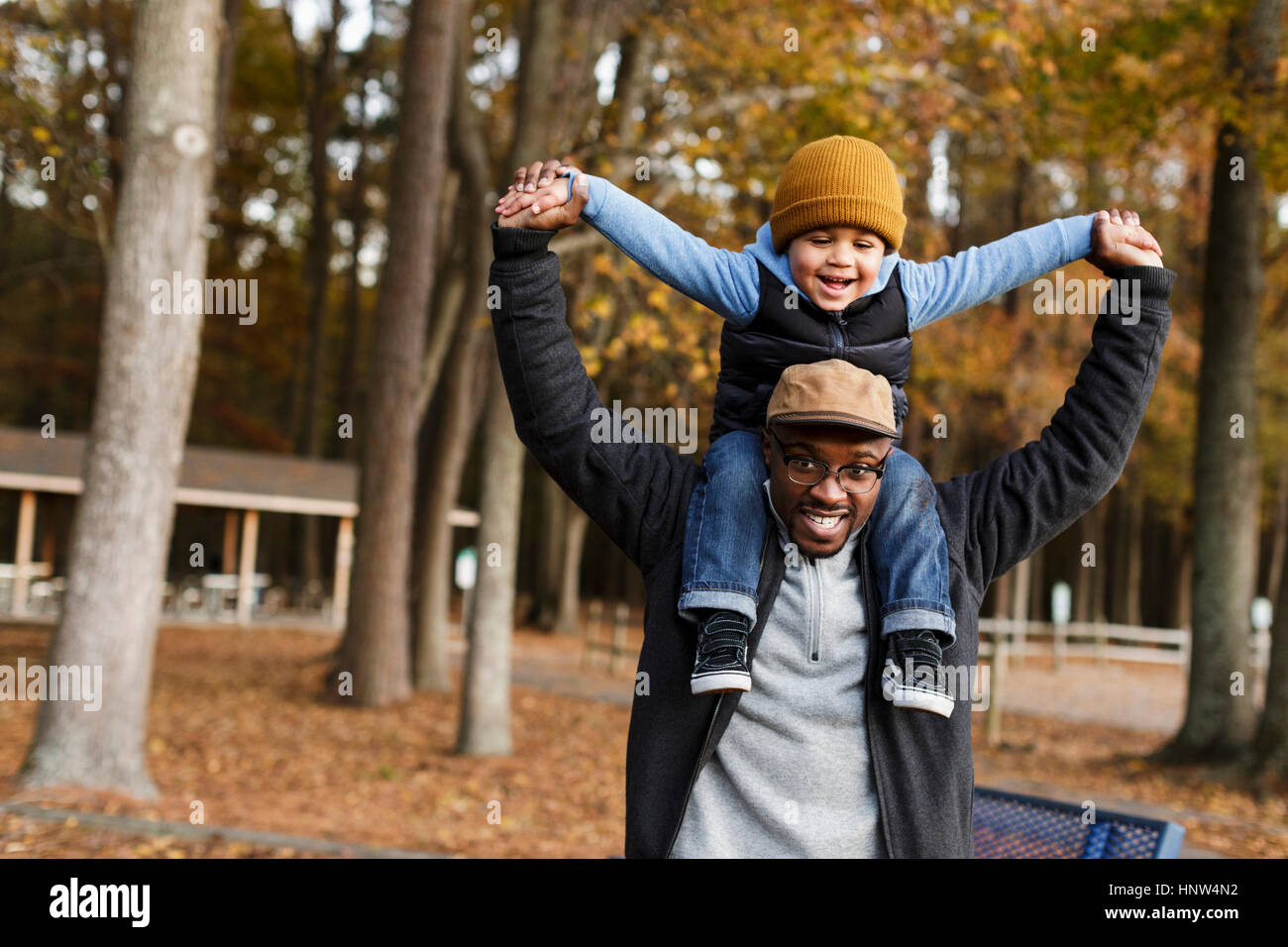Father carrying son on shoulders in park Banque D'Images