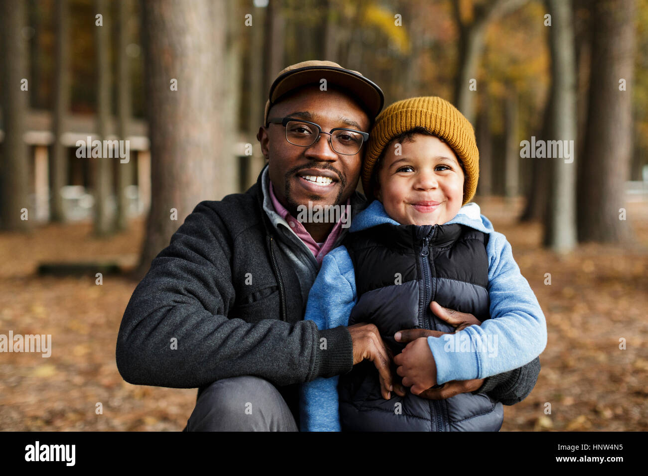 Portrait of smiling father and son hugging in park Banque D'Images