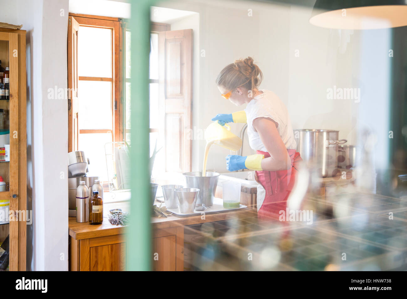 Young woman pouring liquid savon lavande savon fait à la main dans le bol en atelier Banque D'Images