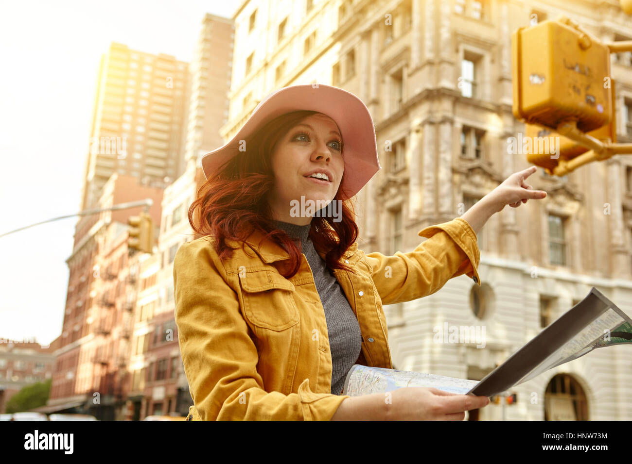 Jeune femme touriste avec longs cheveux rouges saluant une cabine sur street, Manhattan, New York, USA Banque D'Images