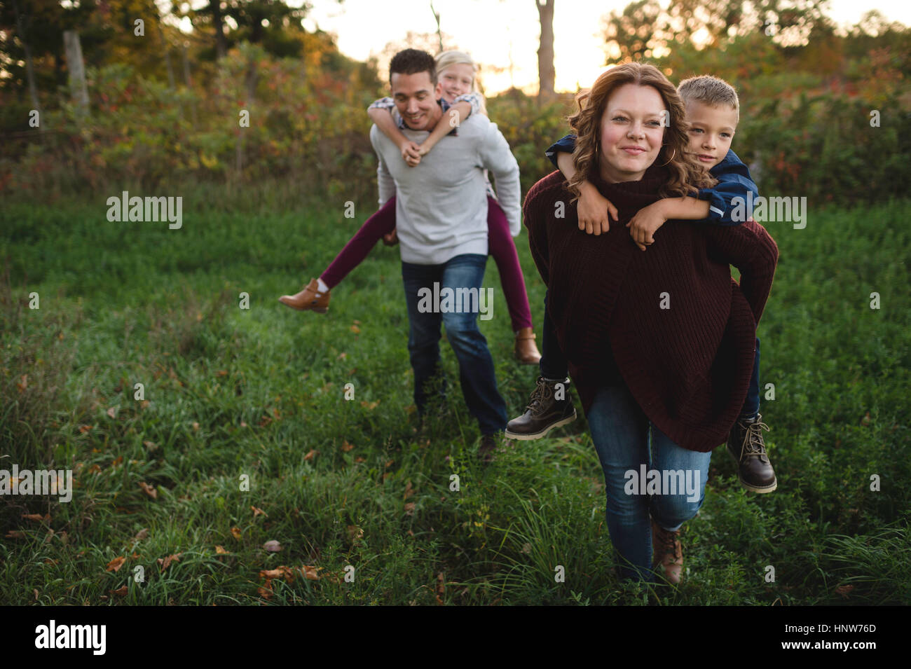 Donner aux enfants les parents piggy back in field Banque D'Images