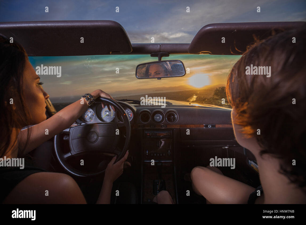 Deux jeunes femmes en voiture décapotable, conduite le long de la route panoramique, vue arrière Banque D'Images