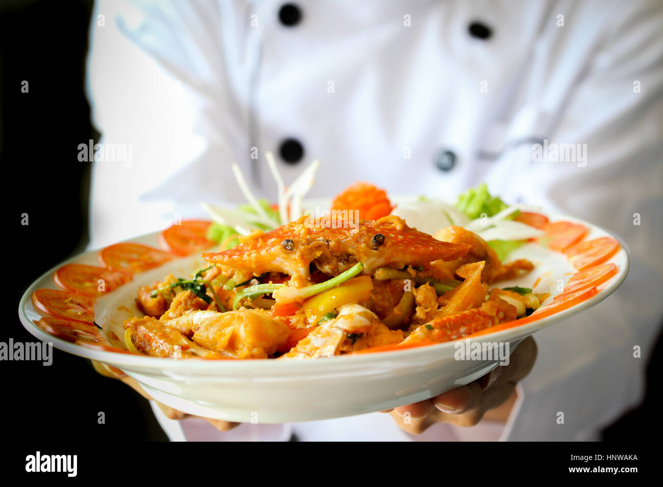 Le chef est fier de présenter le crabe au curry à la noix de coco en arrière-plan dramatique sombre Banque D'Images