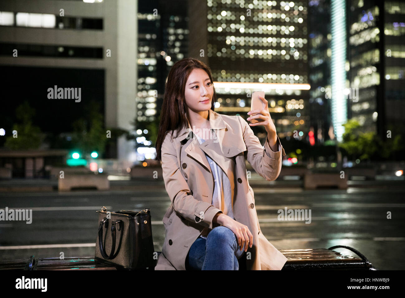 Young smiling woman with smartphone at night Banque D'Images