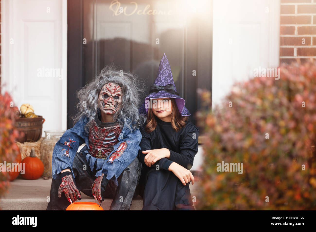 Les amis déguisés en sorcière et zombie, assis à l'avant l'étape d'accueil Banque D'Images
