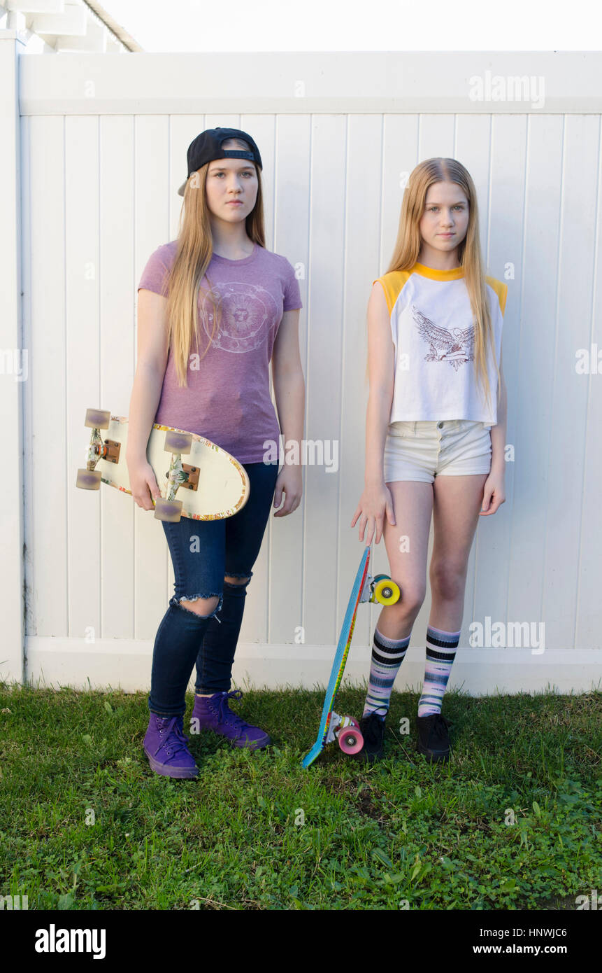 Portrait de deux jeunes sœurs dans jardin skateboarder Banque D'Images