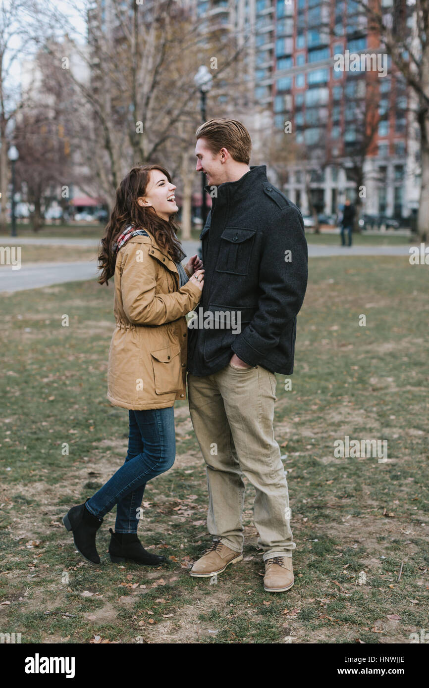 Jeune couple debout à l'extérieur, face à face, laughing Banque D'Images