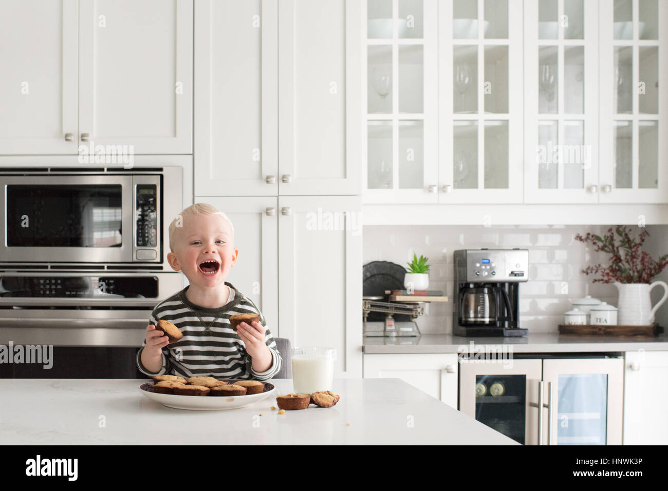 Jeune garçon dans la cuisine, tenant des gâteaux fraîchement préparés, smiling Banque D'Images