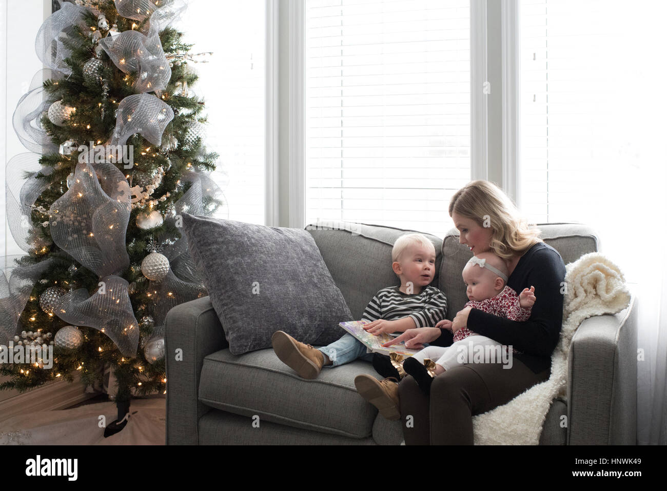 La mère et l'enfant assis sur un canapé, looking at book Banque D'Images