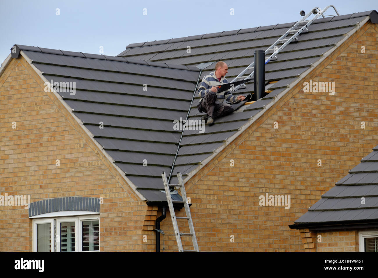 Workman sur un toit de maison l'installation d'une cheminée Banque D'Images
