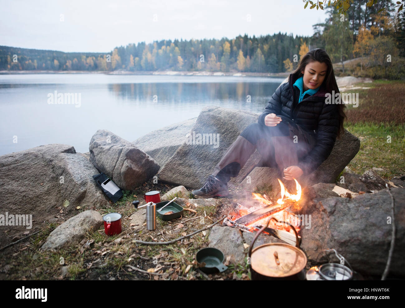 Femme assise près de joie sur Lakeshore pendant camping Banque D'Images