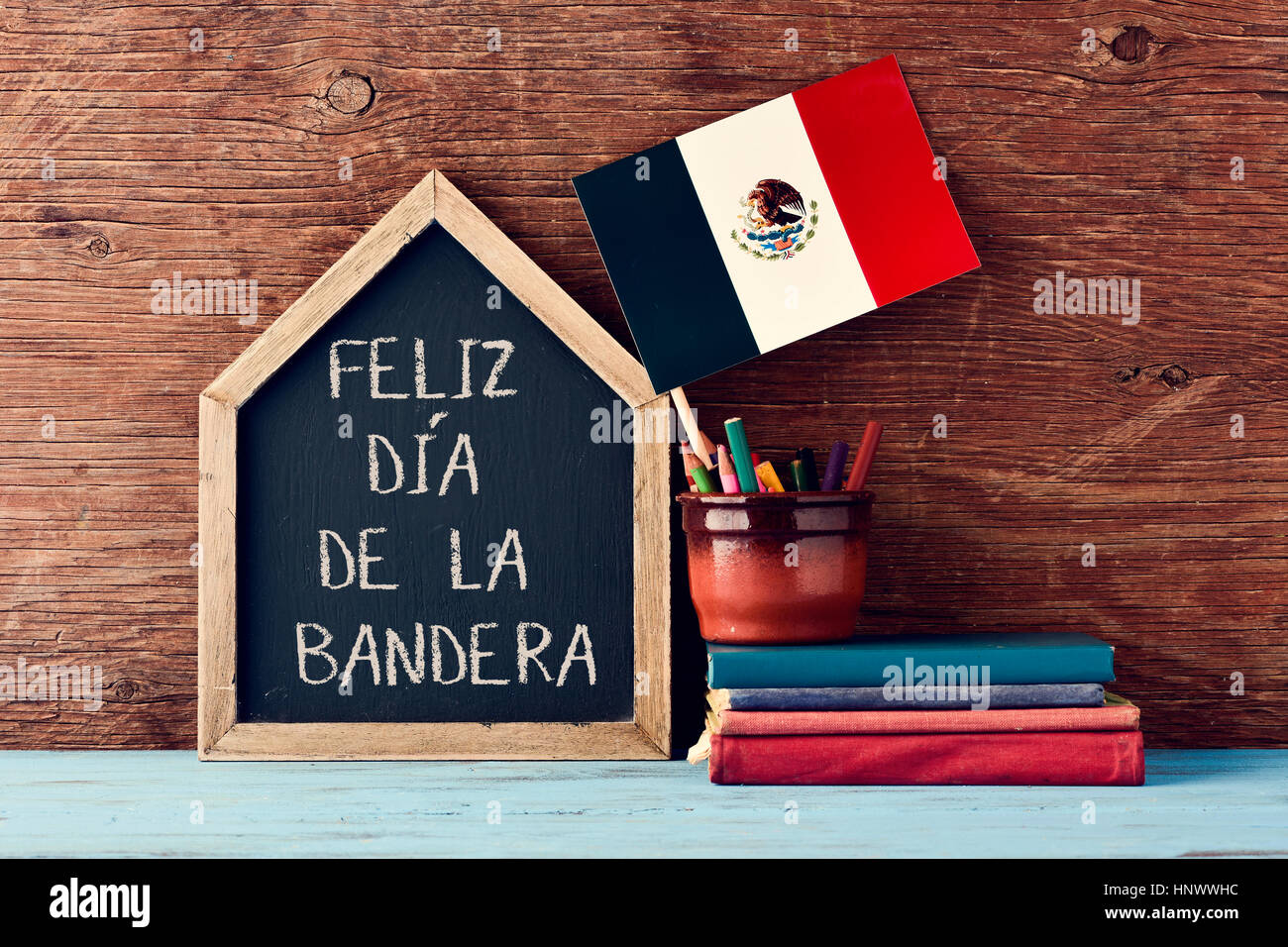 Une maison en forme de tableau sur le texte Feliz Dia de la Bandera, heureux le jour du drapeau écrit en espagnol, le drapeau du Mexique dans un pot avec un peu de crayon crayo Banque D'Images