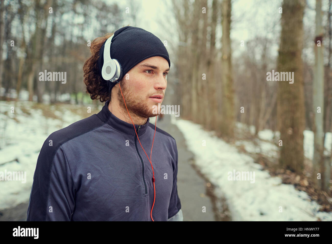 Guy Sports dans les écouteurs et hat au parc Banque D'Images