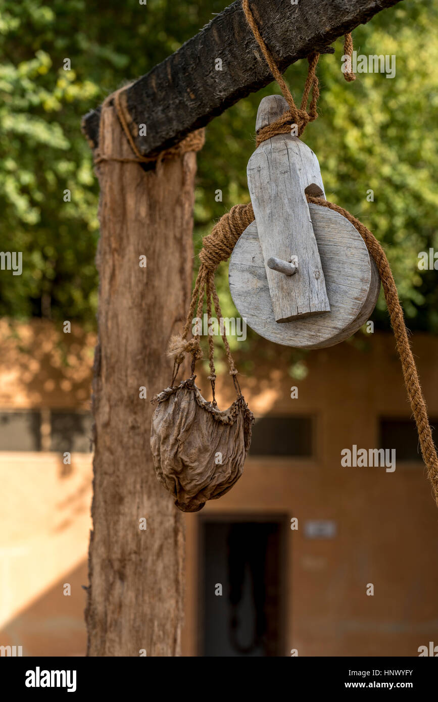 Ancienne poulie en cuir et réservoir d'eau. La poulie en bois avec corde en fibre naturelle tenant un seau de cuir afin de recueillir l'eau d'un puits dans le Moyen-Orient Banque D'Images