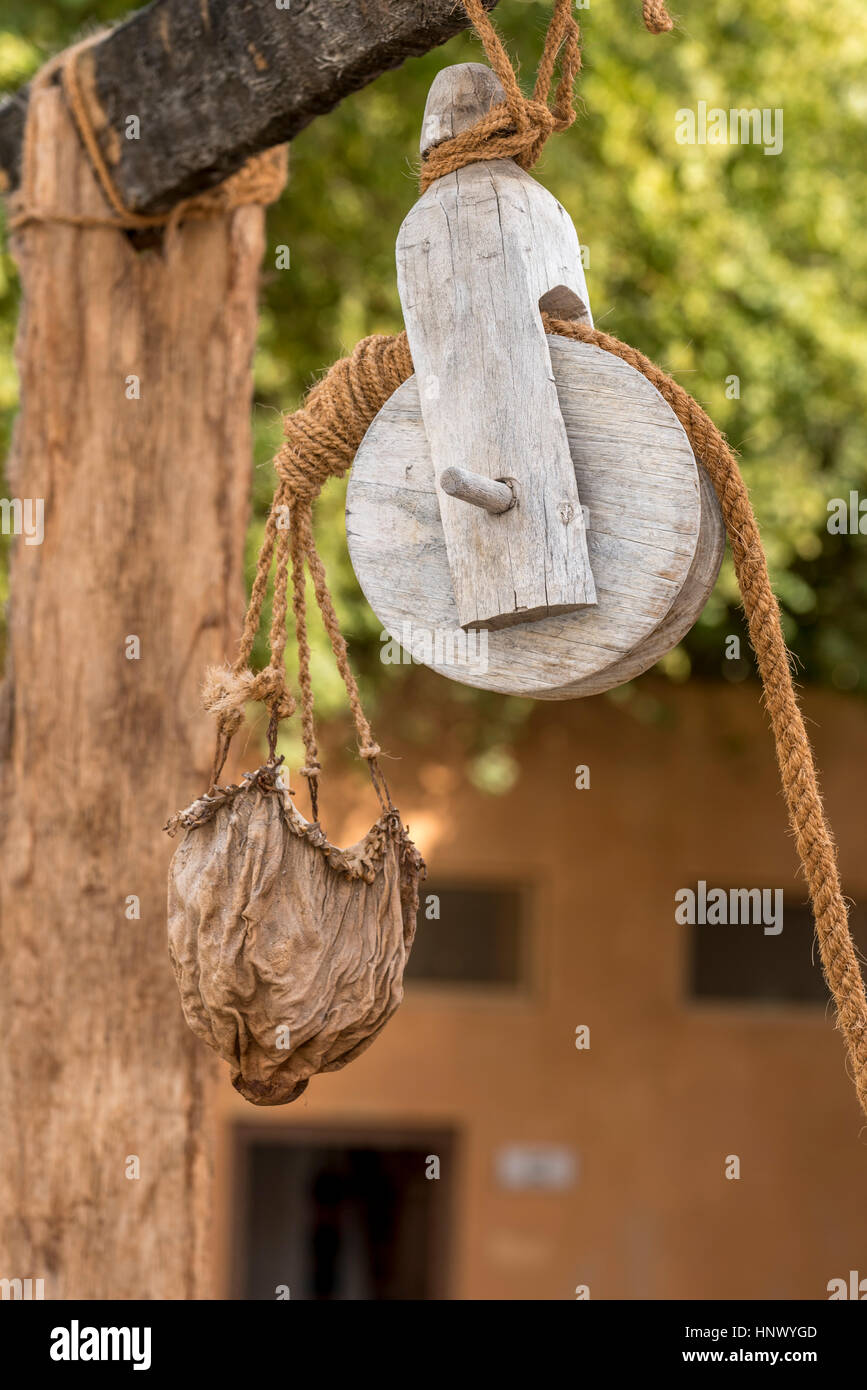 Ancienne poulie en cuir et réservoir d'eau. La poulie en bois avec corde en fibre naturelle tenant un seau de cuir afin de recueillir l'eau d'un puits dans le Moyen-Orient Banque D'Images