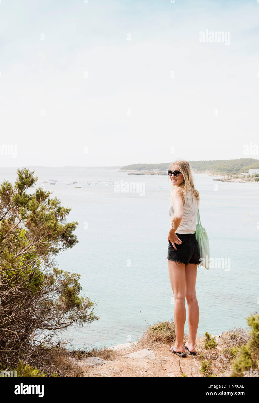 Femme par la mer à la recherche de smiling, Minorque, Espagne Banque D'Images Femme par la mer à la recherche de smiling, Minorque, Espagne Banque D'Images