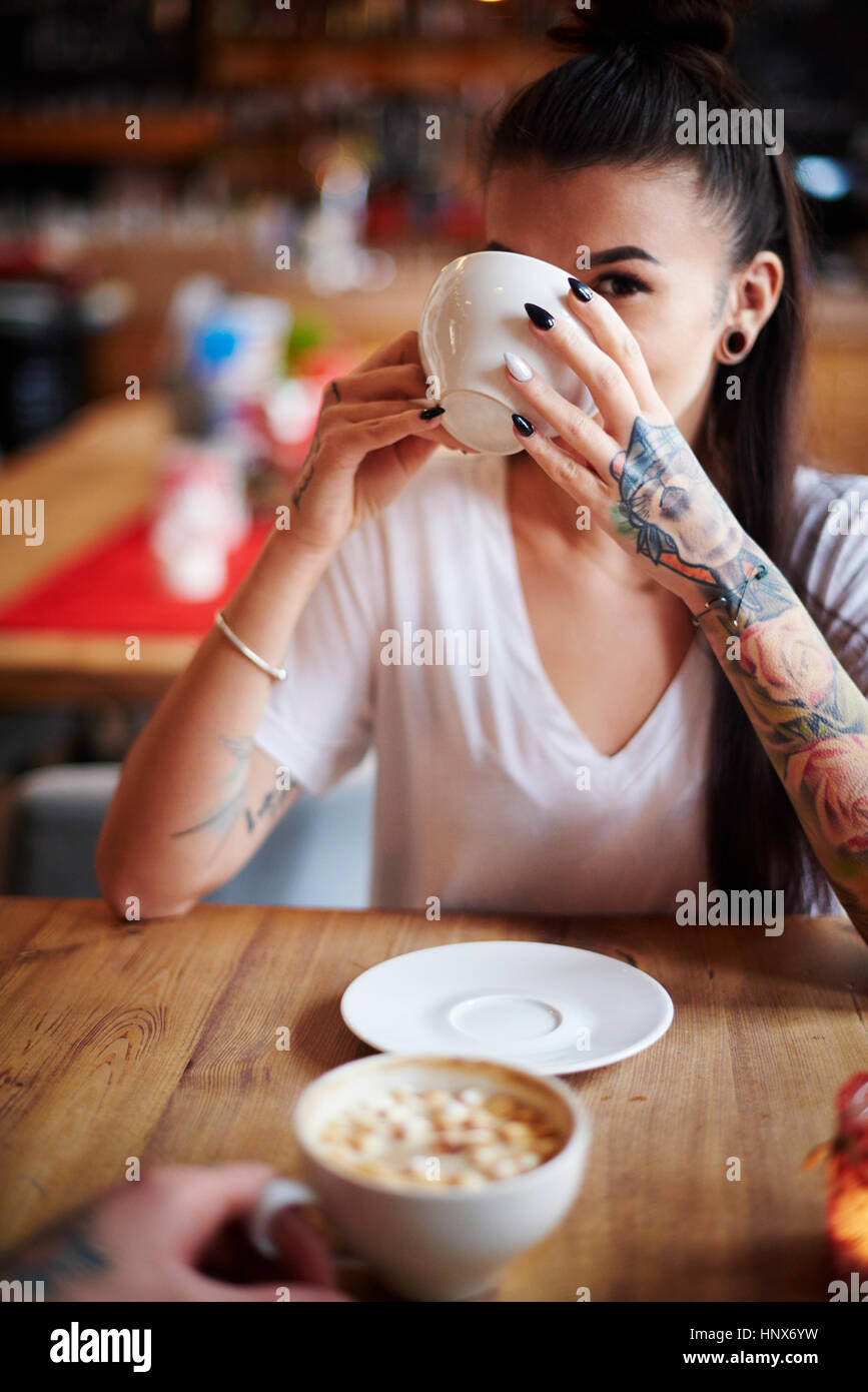 Femme tatouée dans cafe café potable looking at camera Banque D'Images
