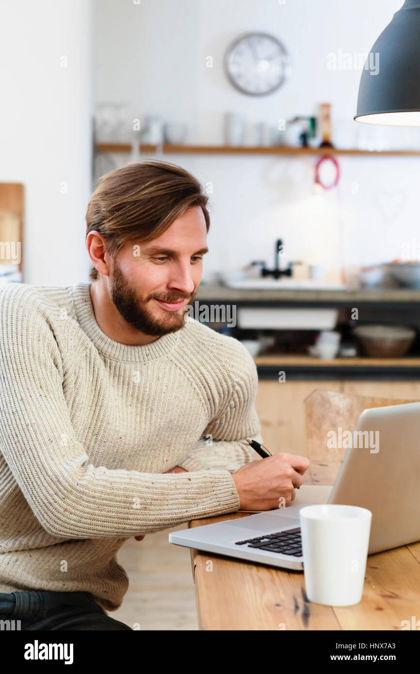 Mid adult man looking at laptop on table Banque D'Images