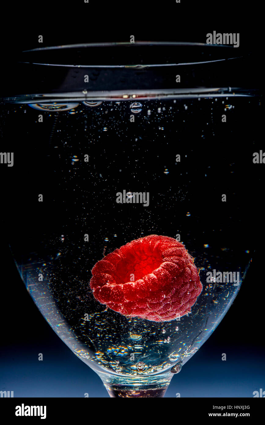 Le verre clair d'eau pétillante avec une framboise dans c Banque D'Images