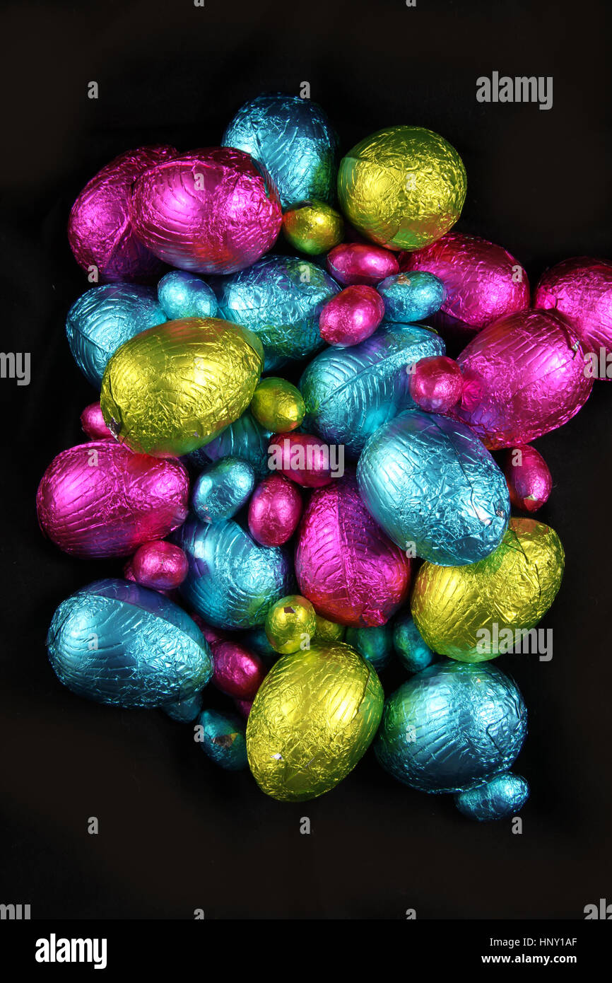 Pile de papier aluminium chocolat oeufs de pâques en rose, bleu et vert lime. Banque D'Images