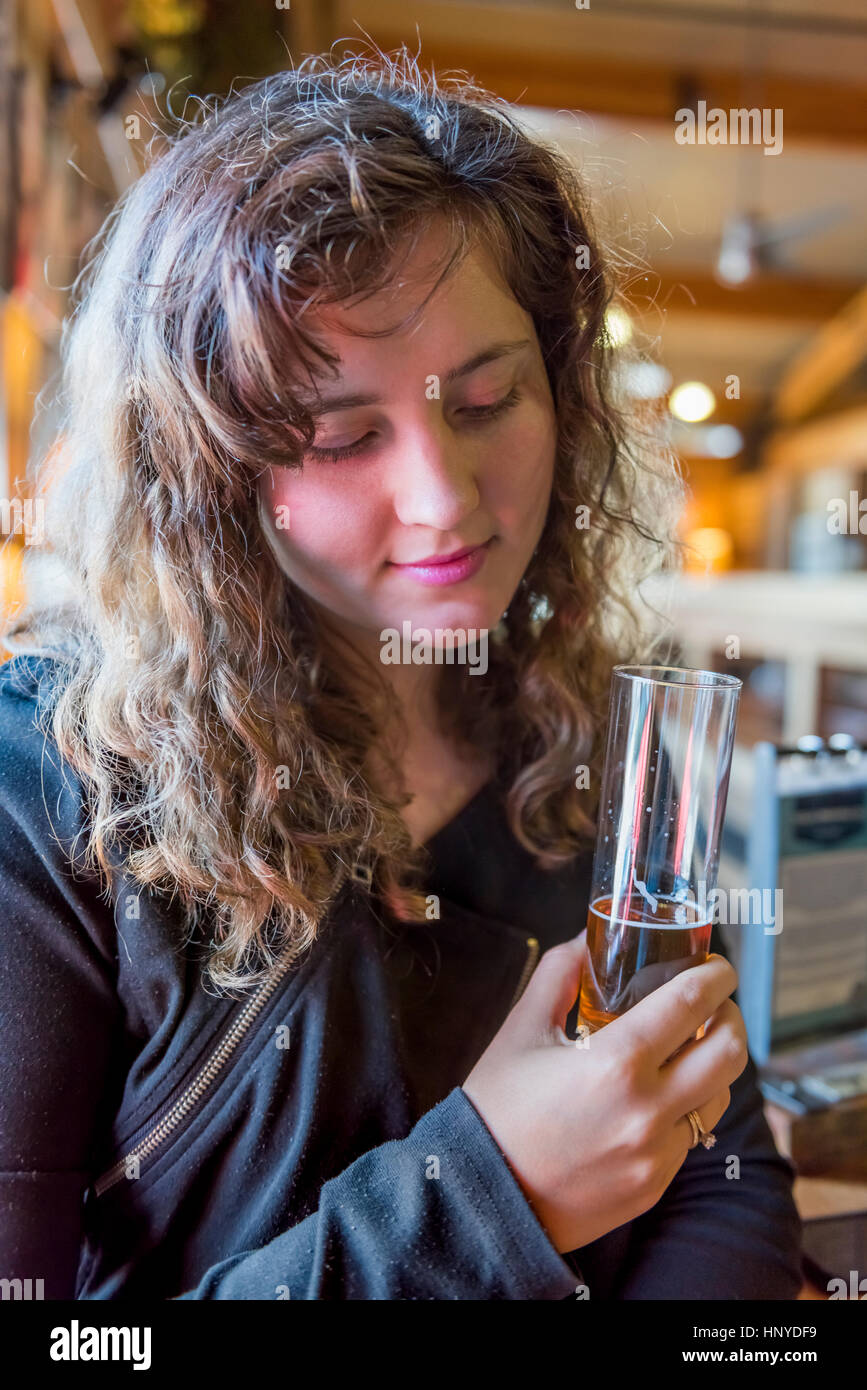 Jeune femme girl holding et dégustation de bière pâle lumière en verre bar bavarois rustique en bois Banque D'Images
