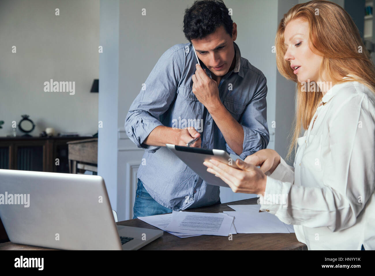 Couple faisant affaires avec téléphone portable et tablette numérique à la maison Banque D'Images